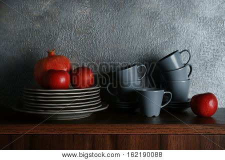 Set of dinnerware and fruits on gray background