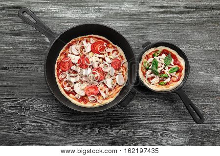 Unbaked pizza with mushroom in pans on wooden table
