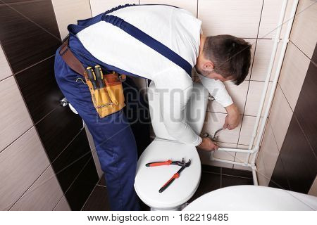 Plumber fixing water hose on toilet cistern