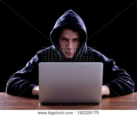 Hacker In A Dark Hoody Sitting In Front Of A Notebook
