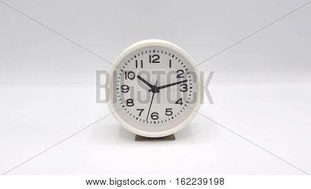 White clock with minute hand and hour hand on white background.