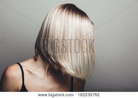 Model with unrecognizable face with blond shiny hair. Woman bob haircut styling.