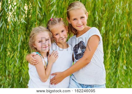 portrait of three young cousins on willow background in summer