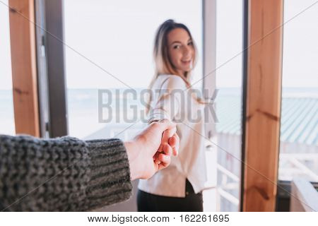 First person view of man holding hand of his smiling woman. Focus on hands