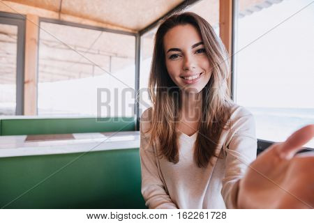 Woman sitting by the table on date in cafe near the sea and touching her man. First-person view