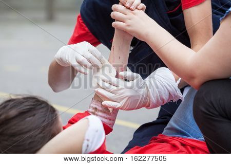 Paramedic giving help to an injured person after accident. First aid training. Arm injury.