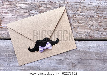 Bow tie on envelope. Props mustache near bow tie. Stylish party invitation.