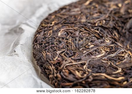 old Shen puerh chinese fermented tea on papyrus paper background macro close-up image