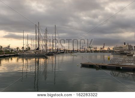 Sailboats and a a cruise ship moored in the harbor, sunrise sunlight shines through the clouds at background port panoramic views