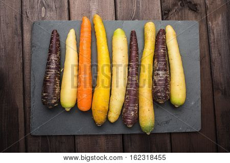 Fresh organic rainbow carrots on a wooden table and slate blackboard