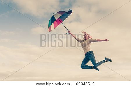 Happiness enjoying weather feeling great concept. Woman jumping with colorful umbrella into clear blue sky