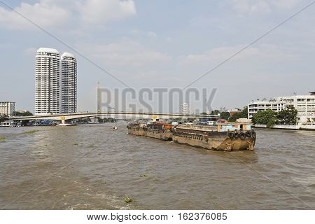 Huge empty cargo barges being towed upstream the Chao Phraya River in Bangkok Thailand