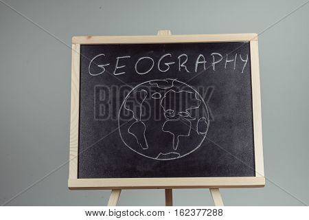 Geography Lesson On Blackboard Or Chalkboard. Written In White Chalk