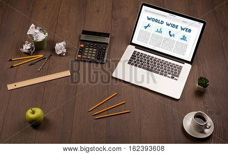 Laptop computer on wooden desk with office suplies