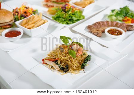 Stir fried spicy spaghetti with seafood on white plate