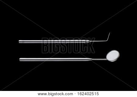 Dental mirror and dental sonde. Image isolated on black background.