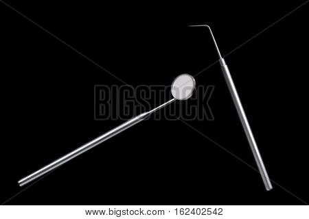 Dental mirror and dental sonde. Image isolated on black background.
