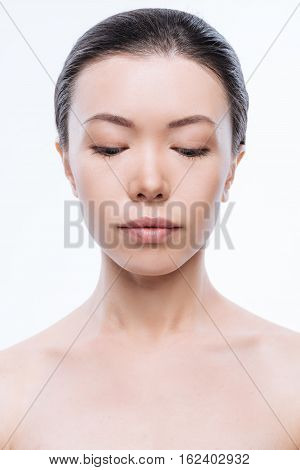 Facial immobility. Peaceful young beautiful woman expressing concentration while standing against white background