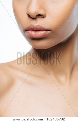 Full of tenderness. Elegant charming young Negroid woman looking at the distance while standing isolated in white background and expressing femininity