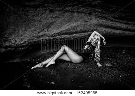 Sexy blond girl in black bikini posing on a beach