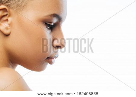Concentrated on my thoughts. Thoughtful attractive young Negroid woman looking down while standing against white background and demonstrating concentration