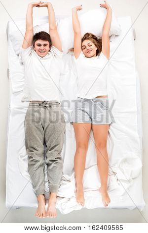 The young lovely couple lying in a white bed, love lconcept, top view