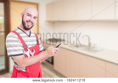 Joyful Male Plumber Texting In The Kitchen