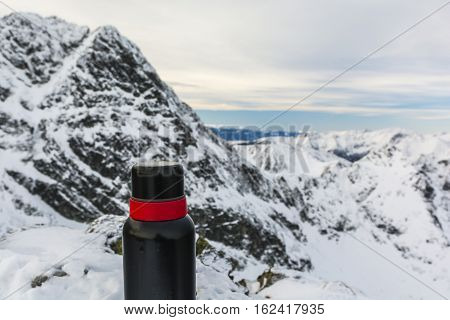 Red And Black Thermos In The Mountains.