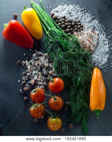 vegetables and spices on a black background, dill and pepper salt