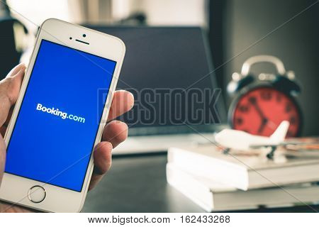 Bangkok, Thailand - March 10, 2017: Business man is using Booking.com application on his iPhone.
