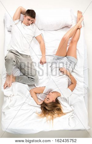 The young lovely couple lying in a white bed, love lconcept, top view