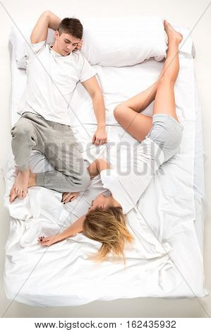 The young lovely couple lying in a white bed, love lconcept, top view