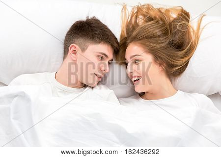 The young lovely couple lying in a white bed, love lconcept, top view
