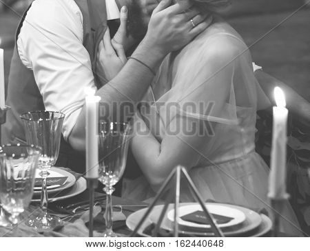 The groom kisses the bride at the holiday table. Black and white