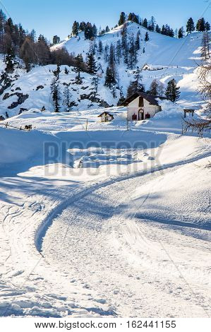 Mountain path in winter time, leading to a little chapel