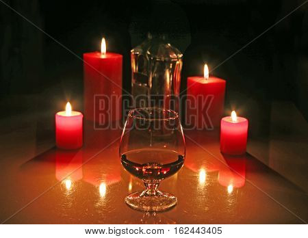 Brandy glass and candles on black background.