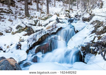 little waterfall on the Alps in winter, with ice and snow