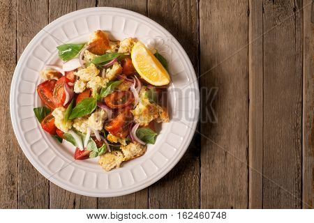 Italian Appetizer salad with tomatoes, bread, bazil mixed with lemon juice on the wooden background