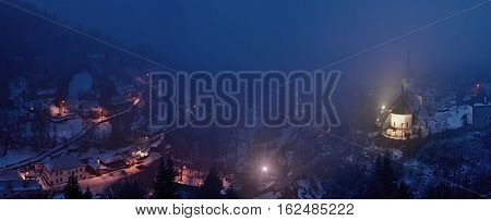 Winter in Slovakia. Old mining village. Historic church in Spania dolina. Fog at night.