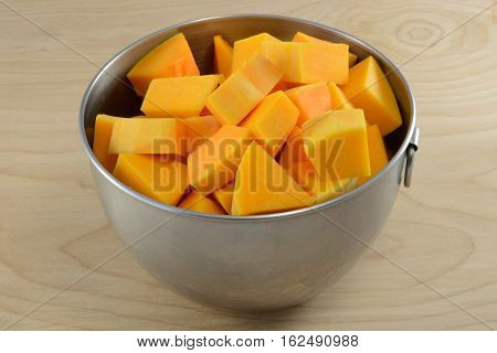 Raw uncooked butternut squash cubes in mixing bowl as cooking preparation