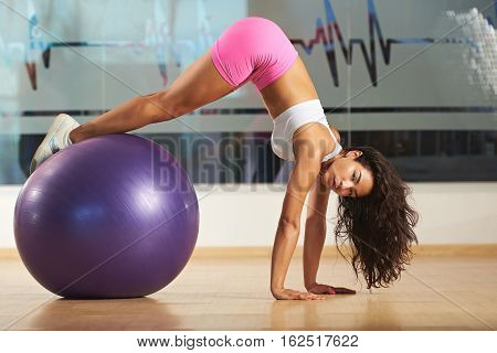 Woman doing fitness with aerobic ball in gym. Aerobic trainer woman