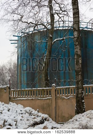 blue building of beige wall with barbed wire, snow, winter