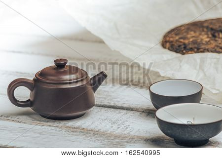 Teapot from Yixing clay for Chinese tea ceremony on rustic wooden background with tea cups and old shu puerh