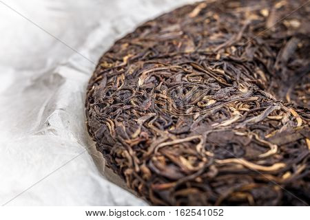 old Shen puerh chinese fermented tea on papyrus paper background macro close-up image