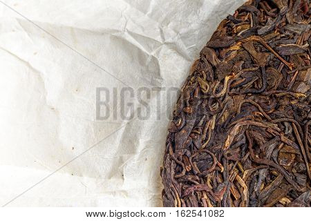 old Shen puerh chinese fermented tea on papyrus paper background with copyspace. Top view