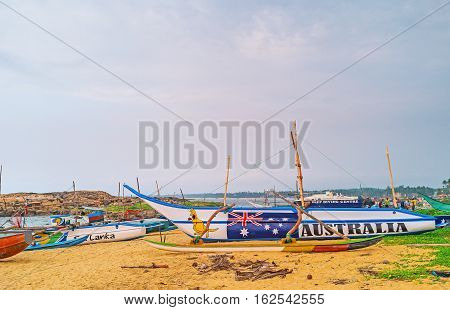 HIKKADUWA SRI LANKA - DECEMBER 5 2016: The walk among the colorful fishing boats on the beach with the fishermen unweigh their catch on background on December 5 in Hikkaduwa.