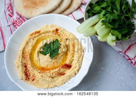 Home classic hummus with celery pitoy.Vid top on gray concrete background. Vegan Food Concept.