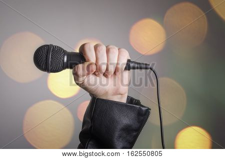The singer left hand holding a dynamic microphone with colourfu bokeh background