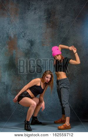 The two attractive girls dancing twerk iat the blue studio background
