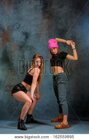 The two attractive girls dancing twerk iat the blue studio background